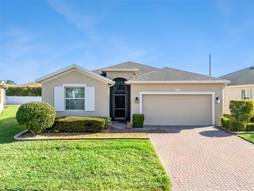 A single-story house with a beige stucco exterior, a brick driveway, and a front lawn — 2733 ATTWATER LOOP, WINTER HAVEN, FL