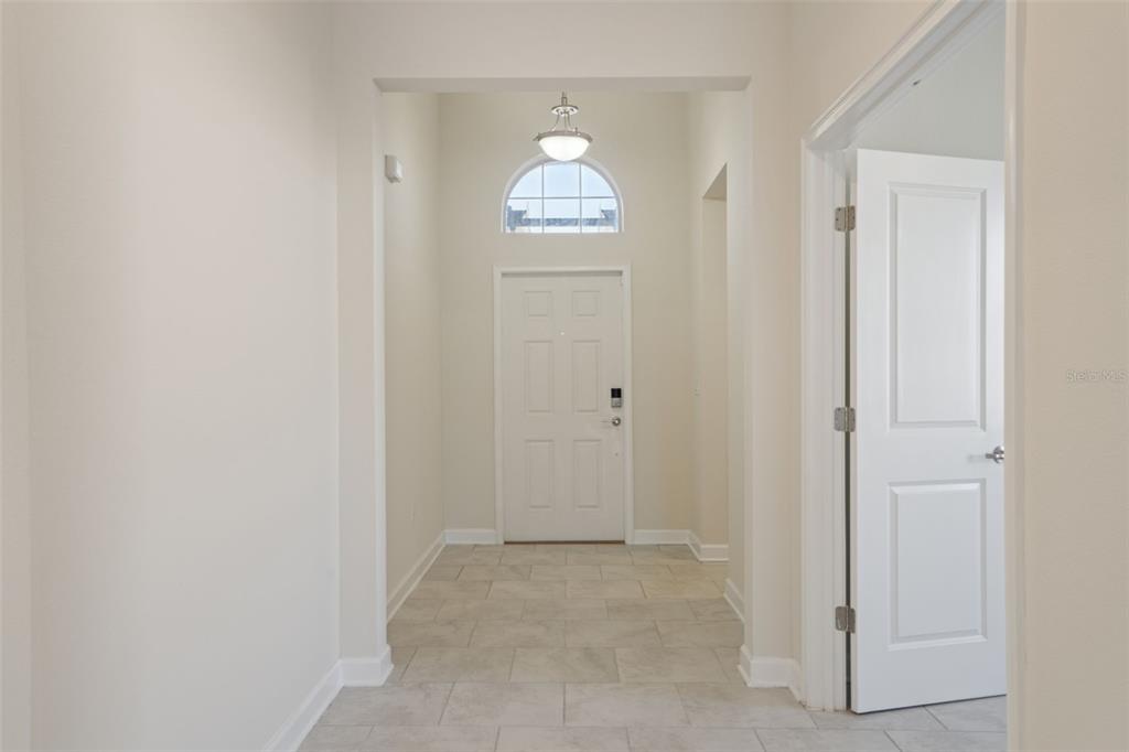 A bright entryway features a white front door with a transom window and tile flooring — 2733 ATTWATER LOOP, WINTER HAVEN, FL