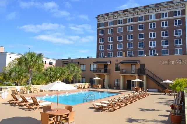 A swimming pool sits on a patio in front of a multi-story brick building — 411 1ST AVENUE N UNIT 702, ST PETERSBURG, FL