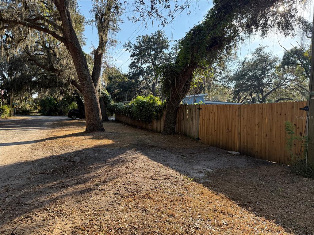 A dirt driveway leads to a wooden fence and large trees on a sunny day — LAKESIDE DRIVE, BRANDON, FL