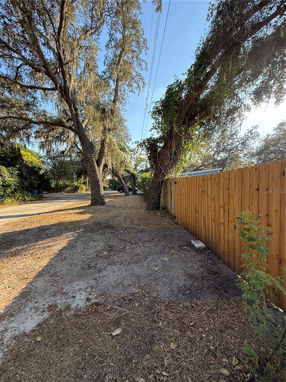 A dirt path runs alongside a wooden fence and large trees with hanging moss — LAKESIDE DRIVE, BRANDON, FL