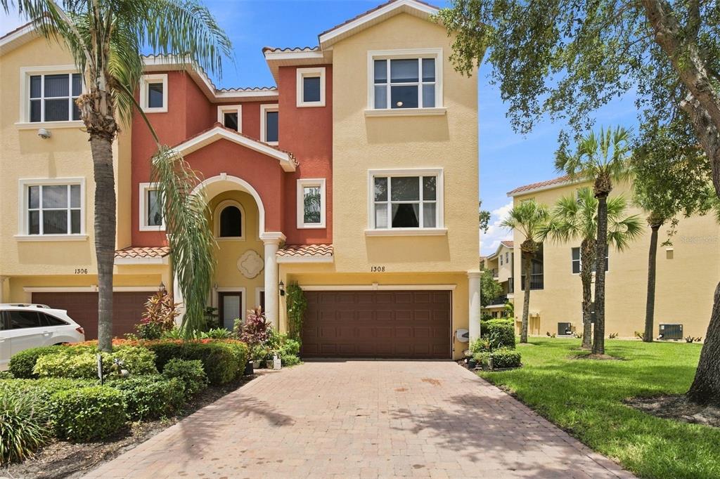 A multi-story residential building with a paved driveway, a two-car garage, and palm trees — 1308 3RD STREET CIRCLE E, PALMETTO, FL