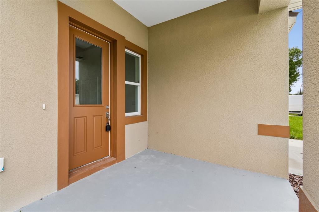 A covered concrete porch features a brown door with a glass panel and a window — 2523 AVENUE E SW, WINTER HAVEN, FL