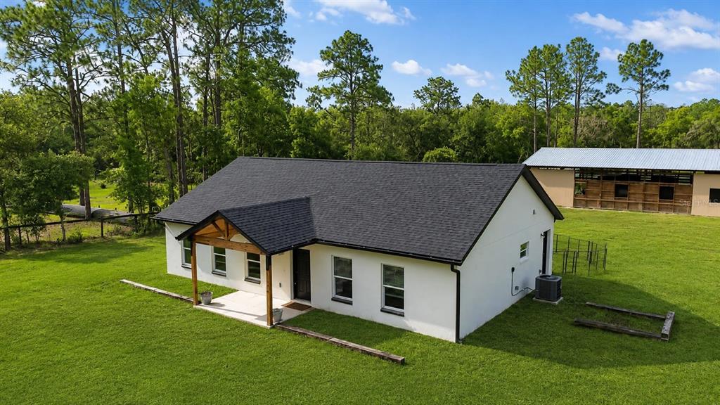 An aerial view of a white single-story house with a black roof and wooden porch — 11670 SE 55TH LANE, MORRISTON, FL