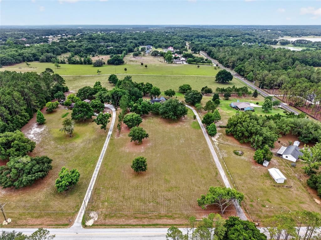 An aerial view shows a large, grassy lot with two driveways and several trees — 20514 BILL COLLINS ROAD, EUSTIS, FL