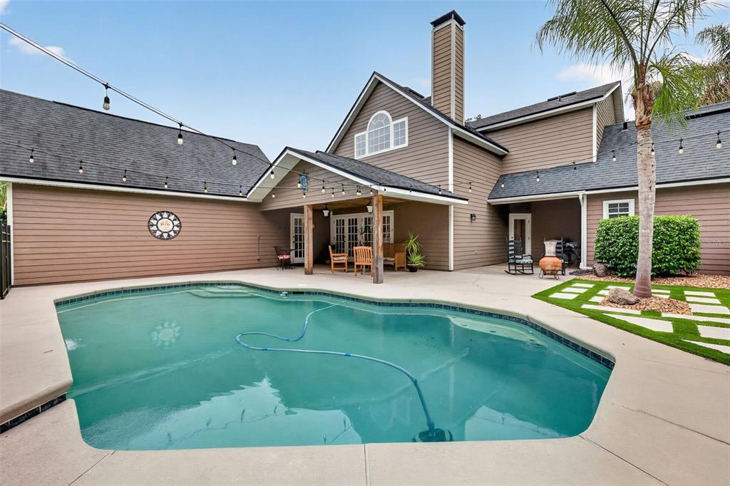 A swimming pool sits on a concrete patio in front of a brown house exterior — 20514 BILL COLLINS ROAD, EUSTIS, FL