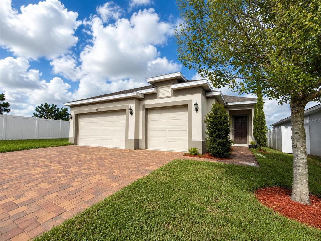 An aerial view shows a single-story house with a brick driveway and a white fence — 179 BLUE CYPRESS DRIVE, DAVENPORT, FL
