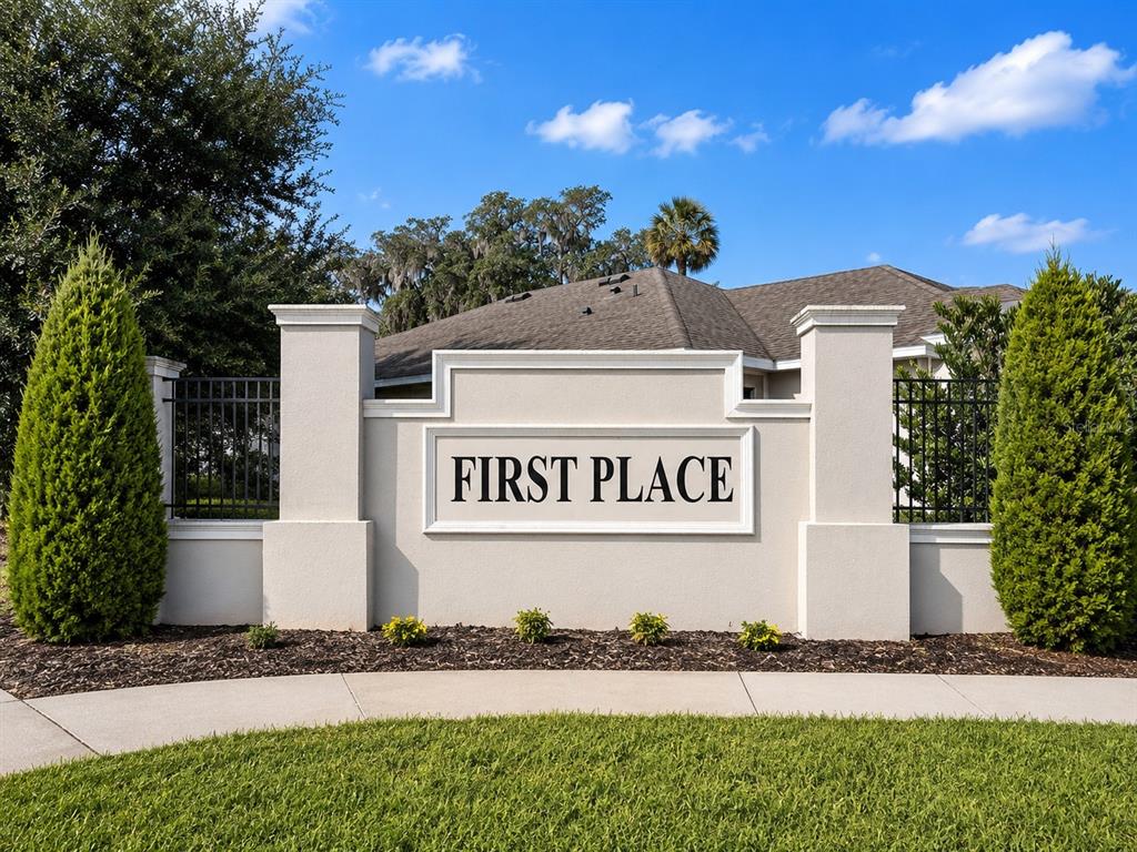 A beige stucco monument sign reading First Place stands in front of a residential home — 179 BLUE CYPRESS DRIVE, DAVENPORT, FL