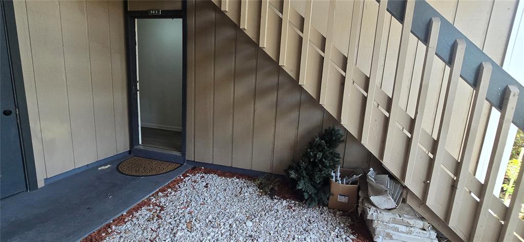 An exterior view shows a doorway labeled 143 beneath a wooden staircase with gravel flooring — 8849 S OLD KINGS RD UNIT 143, JACKSONVILLE, FL