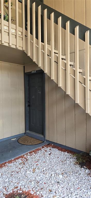A dark front door is situated beneath an outdoor staircase with light-colored wooden railings — 8849 S OLD KINGS RD UNIT 143, JACKSONVILLE, FL