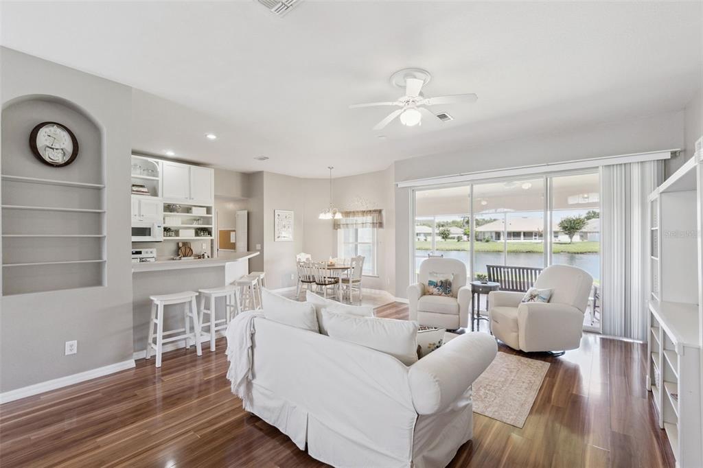A living room with wood floors, white furniture, and a sliding door overlooking a lake — 3805 LAUREL VIEW DRIVE, KISSIMMEE, FL