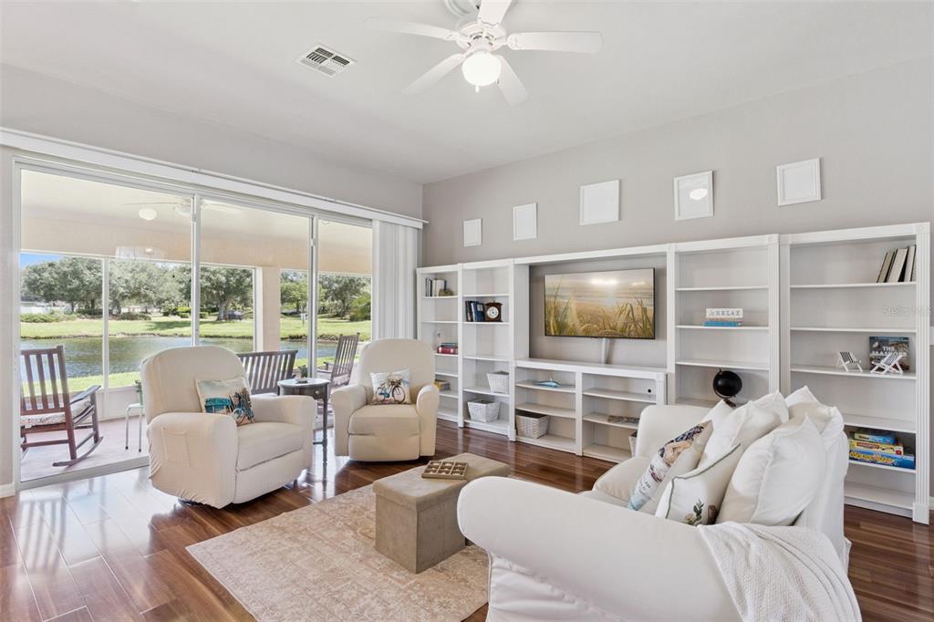 A living room features white built-in shelving, a television, two armchairs, and a sliding glass door — 3805 LAUREL VIEW DRIVE, KISSIMMEE, FL