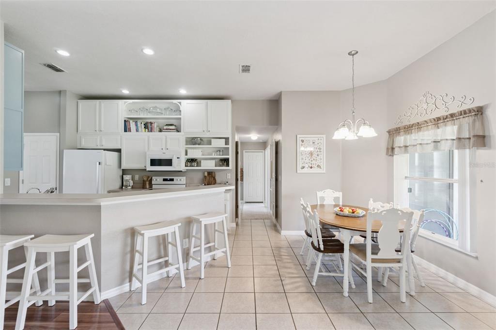 A kitchen with white cabinets and a breakfast bar opens to a dining area — 3805 LAUREL VIEW DRIVE, KISSIMMEE, FL