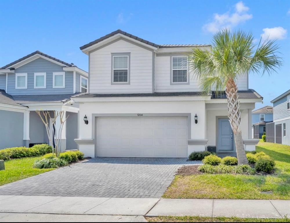 A two-story house with a white stucco and siding exterior, a two-car garage, and palm tree — 7204 OAKMOSS LOOP, DAVENPORT, FL