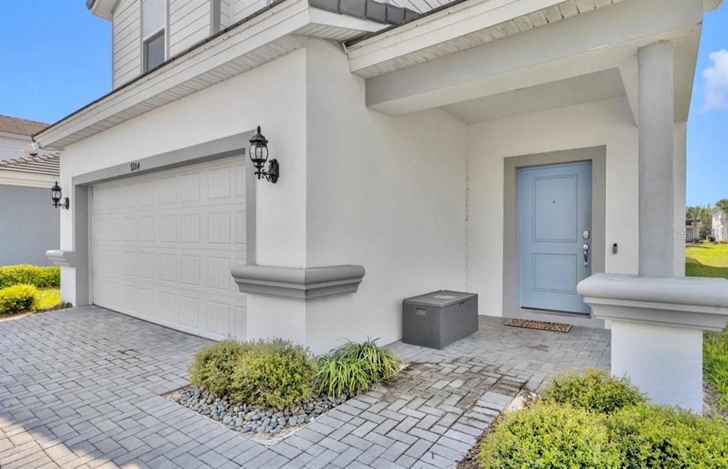 A light blue front door sits beside a white garage and a paved walkway — 7204 OAKMOSS LOOP, DAVENPORT, FL
