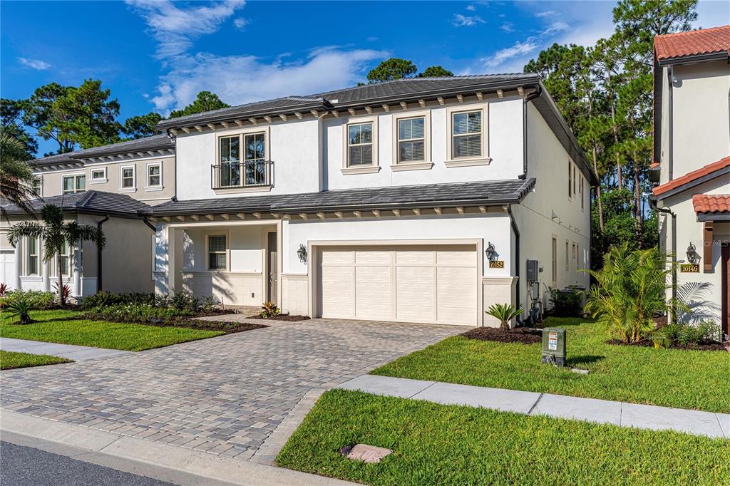A two-story house with a white stucco exterior, a paved driveway, and a two-car garage — 10152 ROYAL ISLAND COURT, ORLANDO, FL