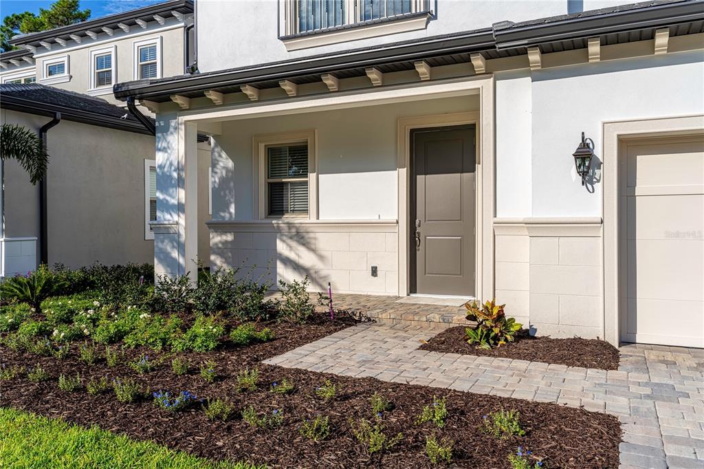 The exterior of a modern house features a covered entryway, a gray door, and landscaping — 10152 ROYAL ISLAND COURT, ORLANDO, FL