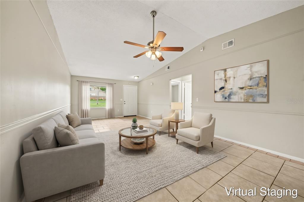 A living room with light-colored tile flooring, a vaulted ceiling, and a ceiling fan — 1188 WOODMAN WAY, ORLANDO, FL