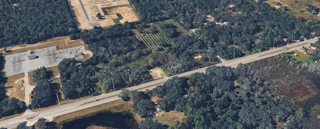 An aerial view shows a wooded lot with a small building near a paved road — 101 COLLINS ROAD, OSTEEN, FL