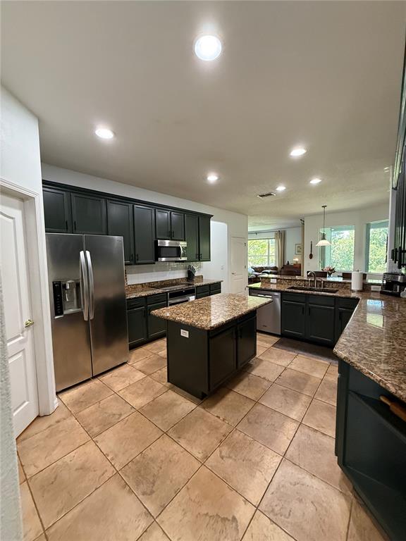 A kitchen features dark cabinetry, granite countertops, a central island, and stainless steel appliances — 26620 SHOREGRASS DRIVE, WESLEY CHAPEL, FL