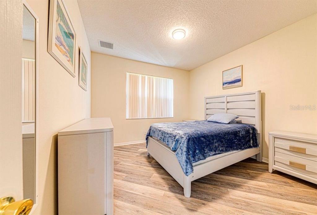 A bedroom features a white bed frame, light wood-look flooring, and a white dresser — 360 TUPELO CIRCLE, DAVENPORT, FL