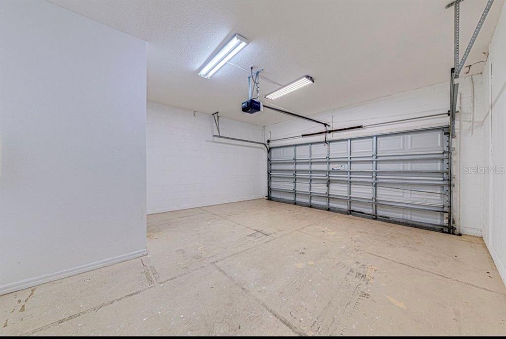 An empty garage with white concrete block walls, a sectional door, and overhead fluorescent lighting — 360 TUPELO CIRCLE, DAVENPORT, FL