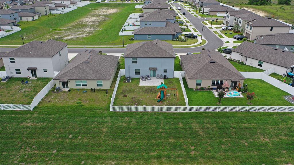 An aerial view shows the backyards and rear exteriors of several suburban houses with white fences — 11693 LAVENDER LOOP, SPRING HILL, FL