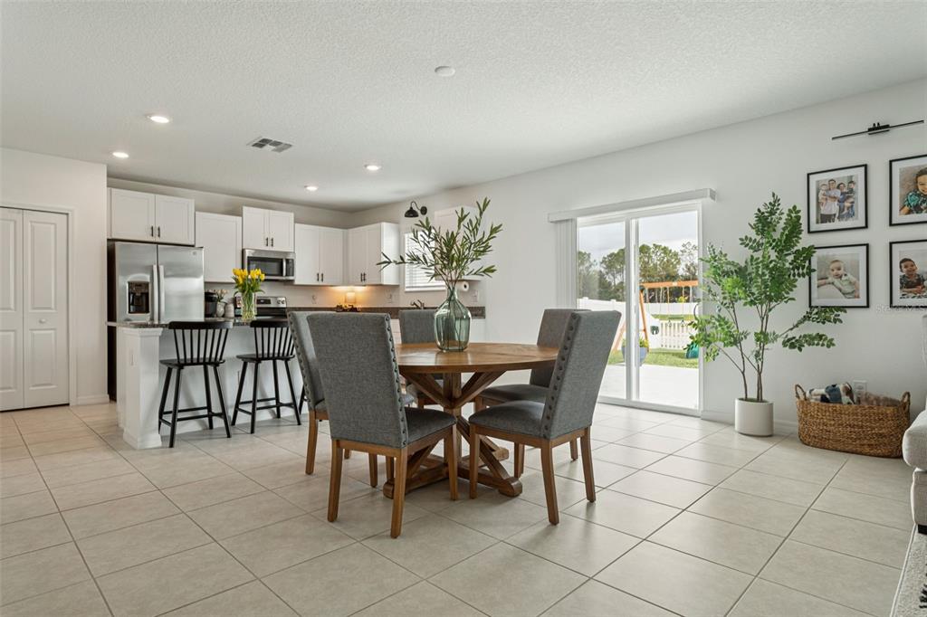 A kitchen with white cabinets and a dining area featuring a round wooden table — 11693 LAVENDER LOOP, SPRING HILL, FL