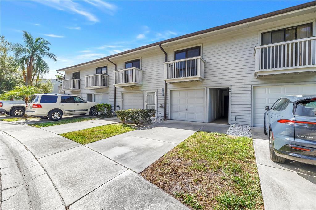 A ground-level view shows two white garage doors flanking a central entryway with number 803 — 6462 92ND PLACE N UNIT 803, PINELLAS PARK, FL