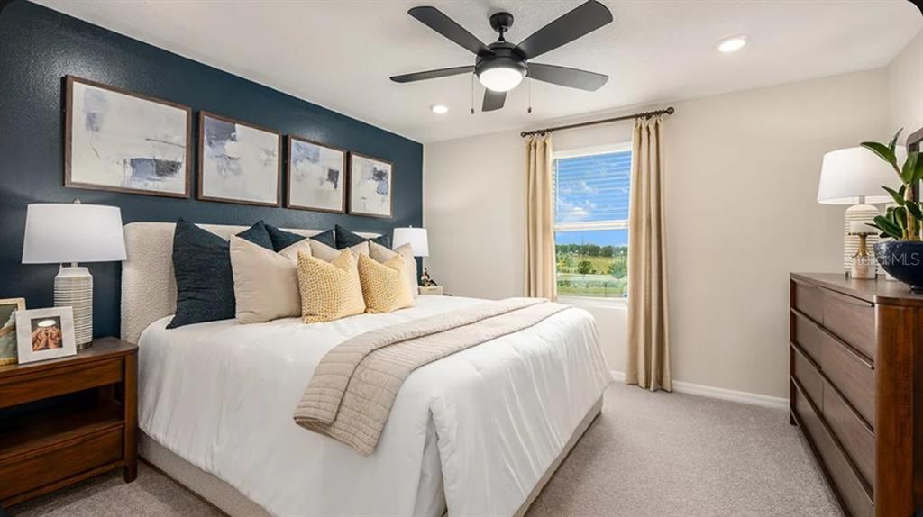 A bedroom features a dark blue accent wall, a king bed, and a wooden dresser — 2513 BALMERINO WAY UNIT 0, MOUNT DORA, FL