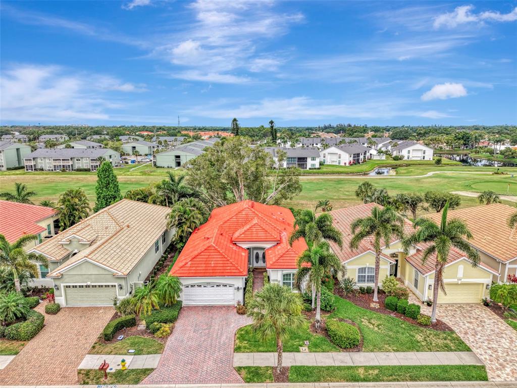 An aerial view shows a residential street with several single-family homes featuring tile roofs — 625 MISTY PINE DRIVE, VENICE, FL