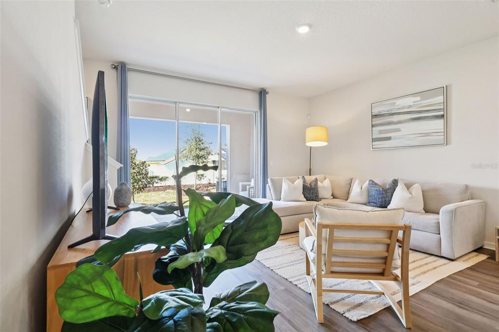 A living room features a sectional sofa, an accent chair, and a sliding glass door — 2753 GLADIOLA ROAD, WINTER HAVEN, FL
