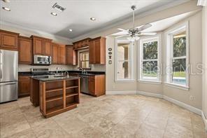 A kitchen features wood cabinets, a center island, stainless steel appliances, and tile flooring — 3620 LEOTA DRIVE, APOPKA, FL