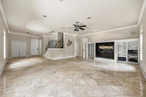 A spacious living room features light-colored tile flooring, a ceiling fan, and a built-in fireplace — 3620 LEOTA DRIVE, APOPKA, FL