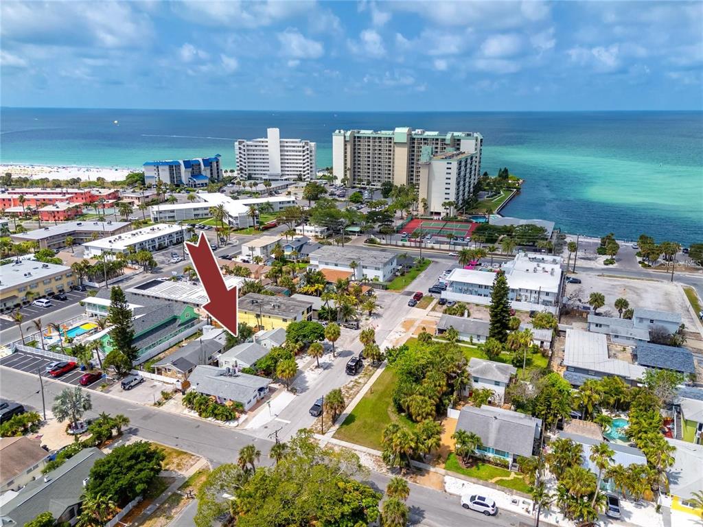 An aerial view shows a coastal neighborhood with a red arrow pointing to a house — 608 72ND AVENUE, ST PETE BEACH, FL