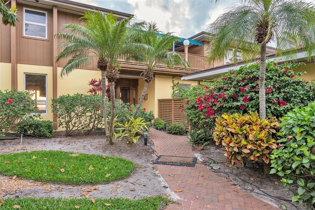 A brick walkway leads to the entrance of a two-story building surrounded by lush landscaping — 1058 ELDORADO AVENUE, CLEARWATER BEACH, FL