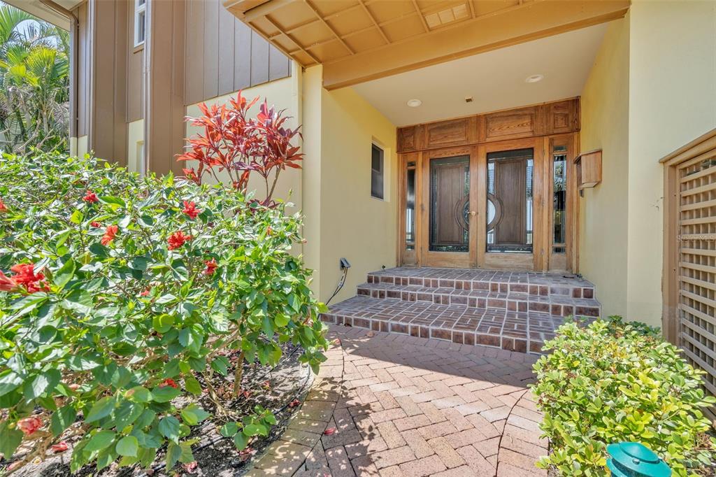 A brick walkway leads to a covered entryway with double wooden doors and brick steps — 1058 ELDORADO AVENUE, CLEARWATER BEACH, FL