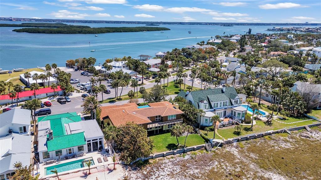 An aerial view shows waterfront homes with pools, palm trees, and a nearby parking lot — 1058 ELDORADO AVENUE, CLEARWATER BEACH, FL