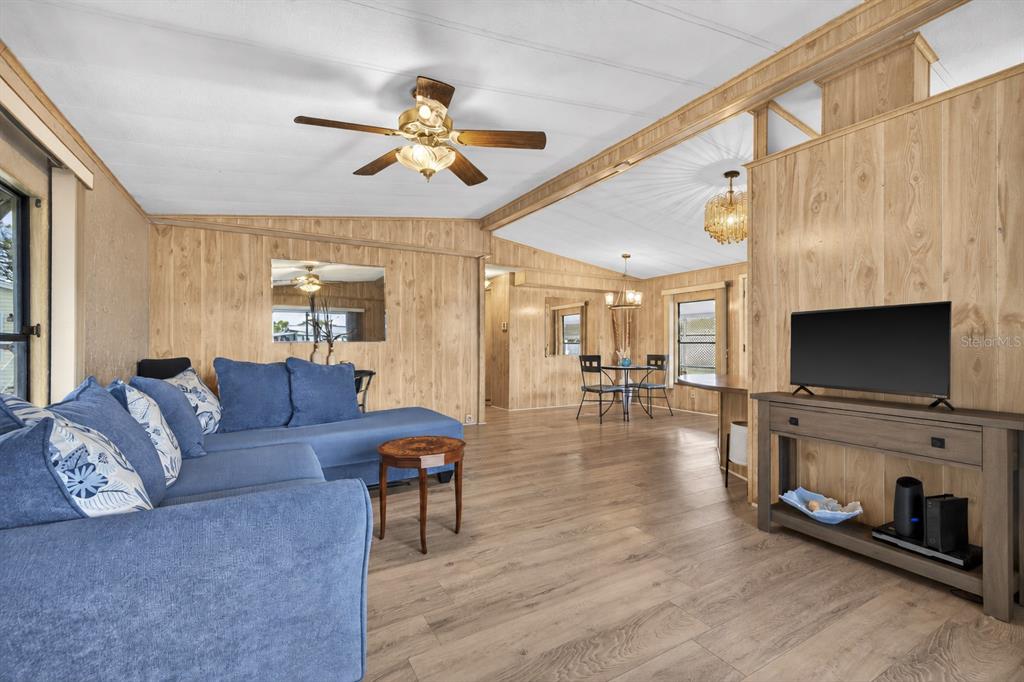 A living room features wood-paneled walls, a blue sectional sofa, and a sliding glass door — 7880 54TH AVENUE N UNIT 38, ST PETERSBURG, FL