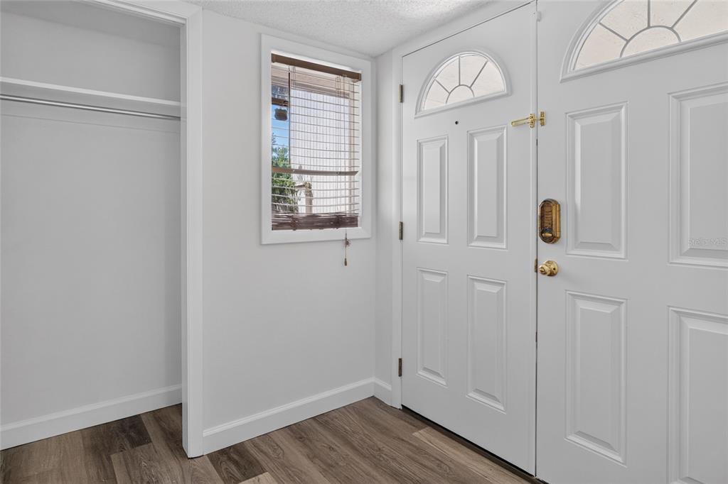 An entryway features a white front door, a closet, a window with blinds, and wood-look flooring — 100 HIDDEN OAK DRIVE, LONGWOOD, FL
