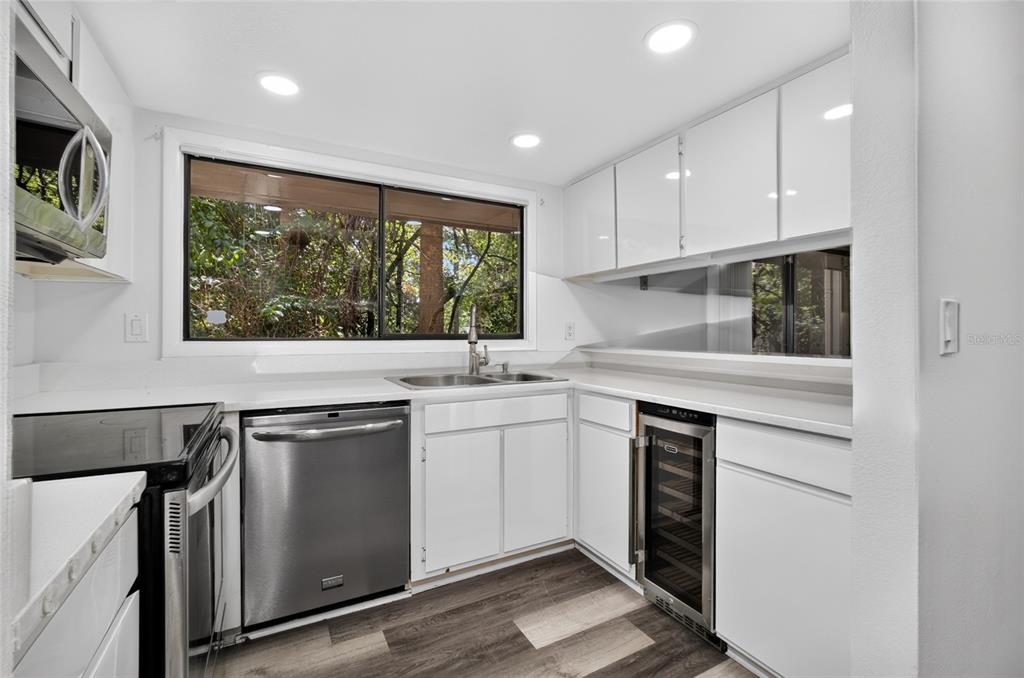 A white kitchen features stainless steel appliances, a window over the sink, and wood-look flooring — 100 HIDDEN OAK DRIVE, LONGWOOD, FL