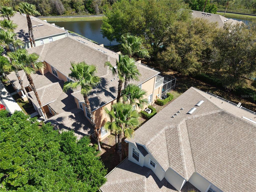 An aerial view shows multi-story residential buildings with tan roofs surrounded by palm trees and greenery — 1711 RETREAT CIRCLE, CLERMONT, FL