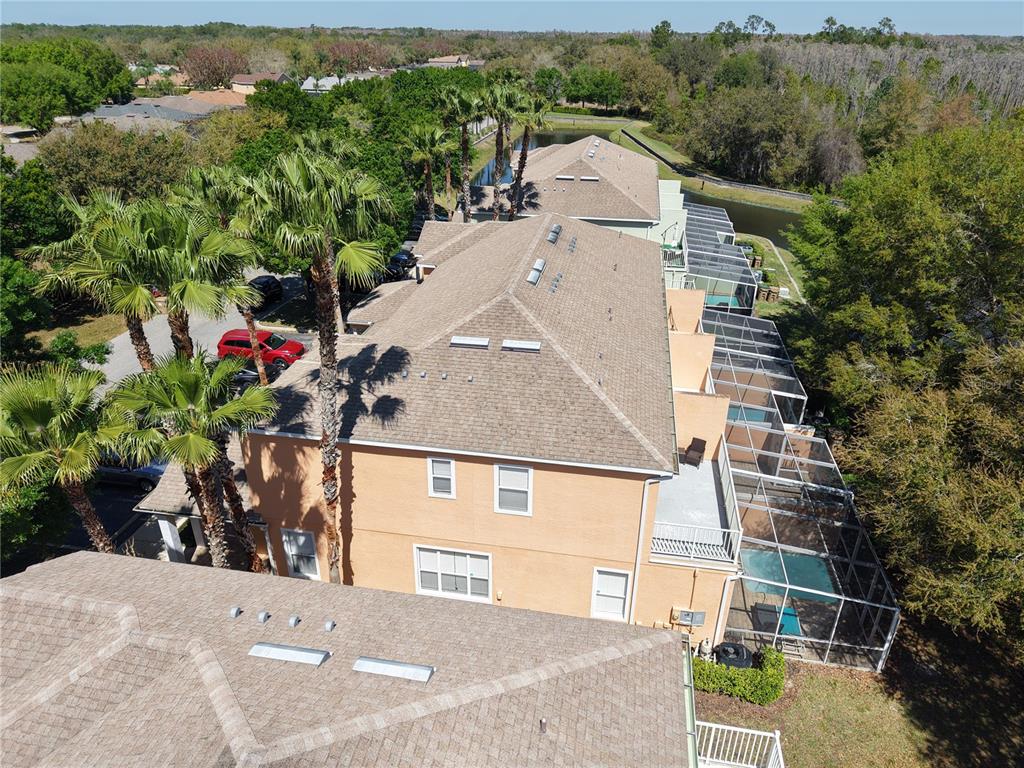 An aerial view shows a multi-story townhouse complex with screened-in lanais and swimming pools — 1711 RETREAT CIRCLE, CLERMONT, FL