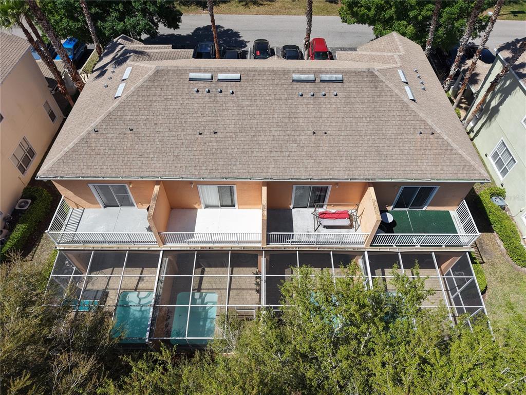 An aerial view shows a multi-unit residential building with screened-in patios and swimming pools — 1711 RETREAT CIRCLE, CLERMONT, FL