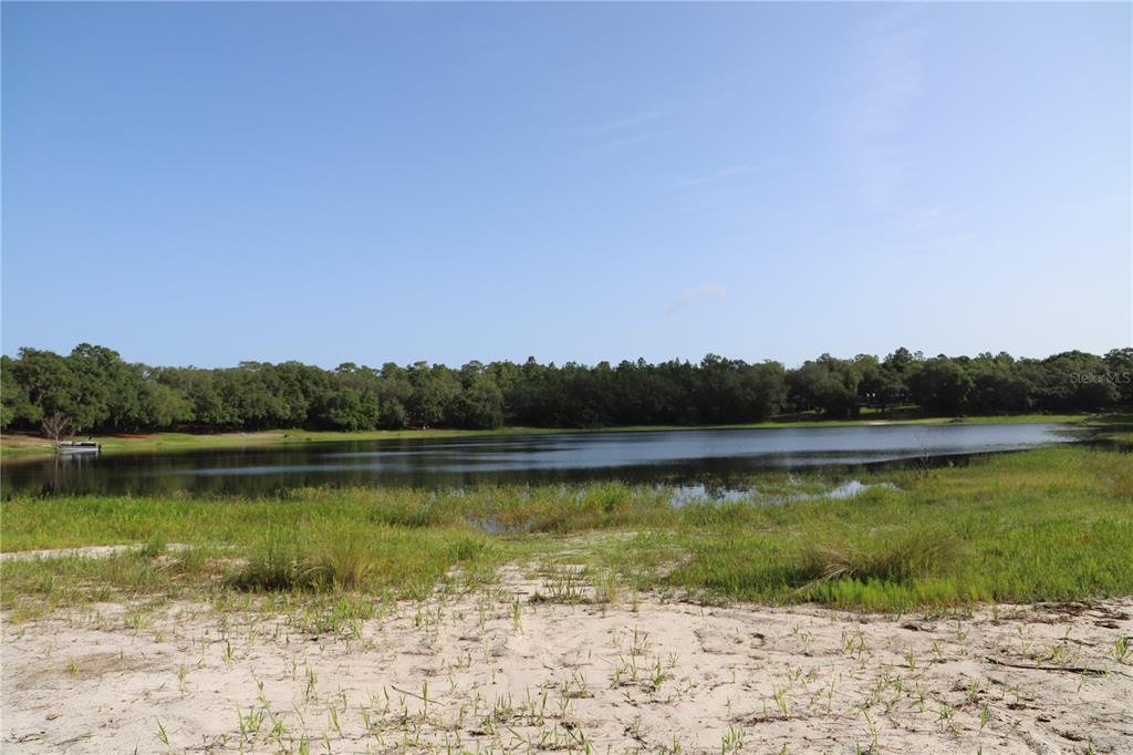 A sandy shoreline leads to a calm lake bordered by a dense line of trees — 00 STATE ROAD 100, KEYSTONE HEIGHTS, FL