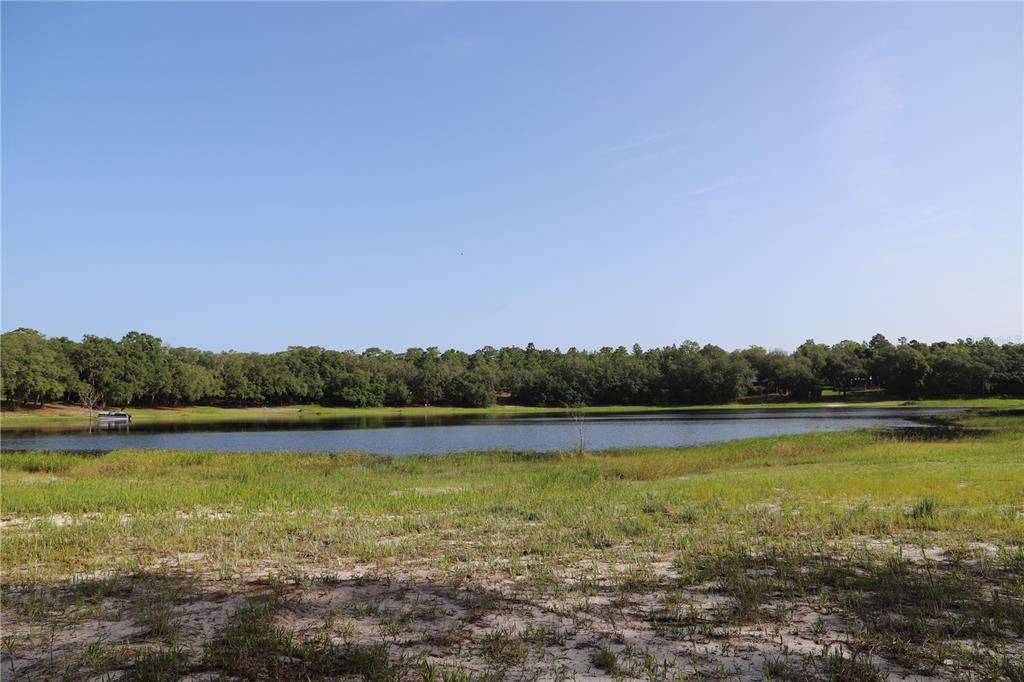 A view of a lake bordered by a grassy shoreline and a dense line of trees — 00 STATE ROAD 100, KEYSTONE HEIGHTS, FL