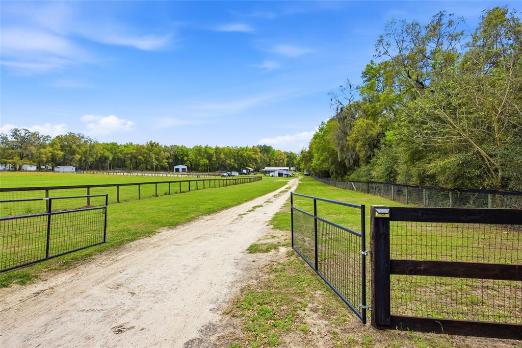 A dirt driveway leads through an open gate toward a barn on a grassy property — 3660 W HWY 329, REDDICK, FL