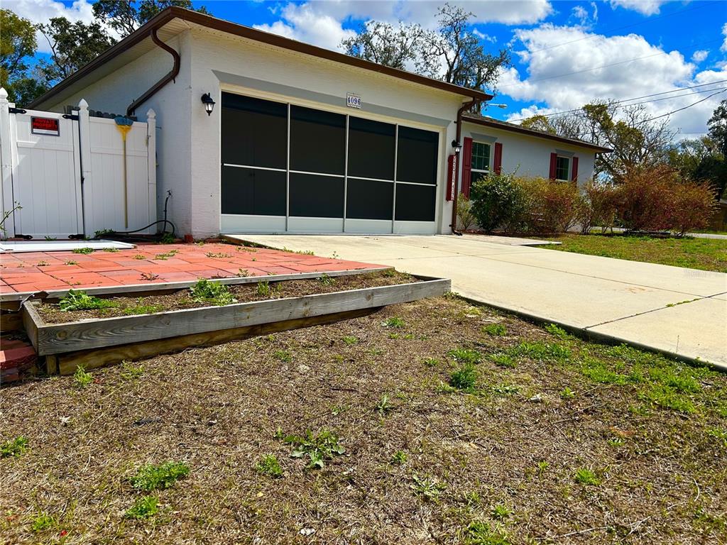 A white house features a garage with a screen door, a paved driveway, and a planter — 4096 THUNDERBIRD AVENUE, SPRING HILL, FL