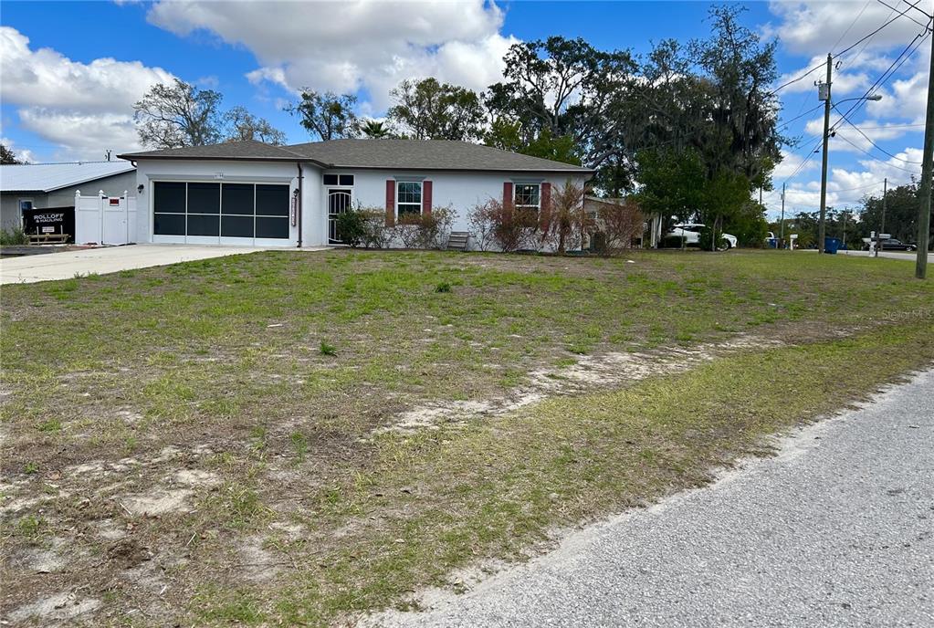 A single-story house with a white exterior, red shutters, and a garage with screen doors — 4096 THUNDERBIRD AVENUE, SPRING HILL, FL