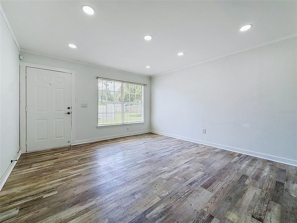 A living room features light gray walls, recessed lighting, and wood-look vinyl plank flooring — 6601 121ST AVENUE UNIT J, LARGO, FL